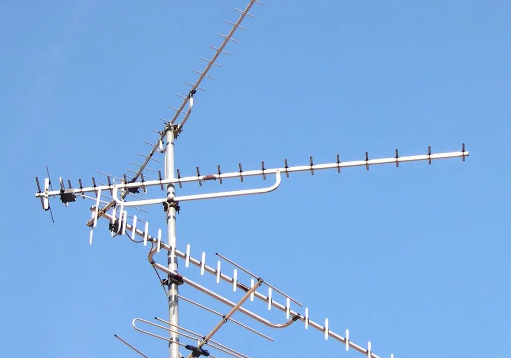 Three long UHF TV aerials and an older VHF aerial on one mast against a blue sky